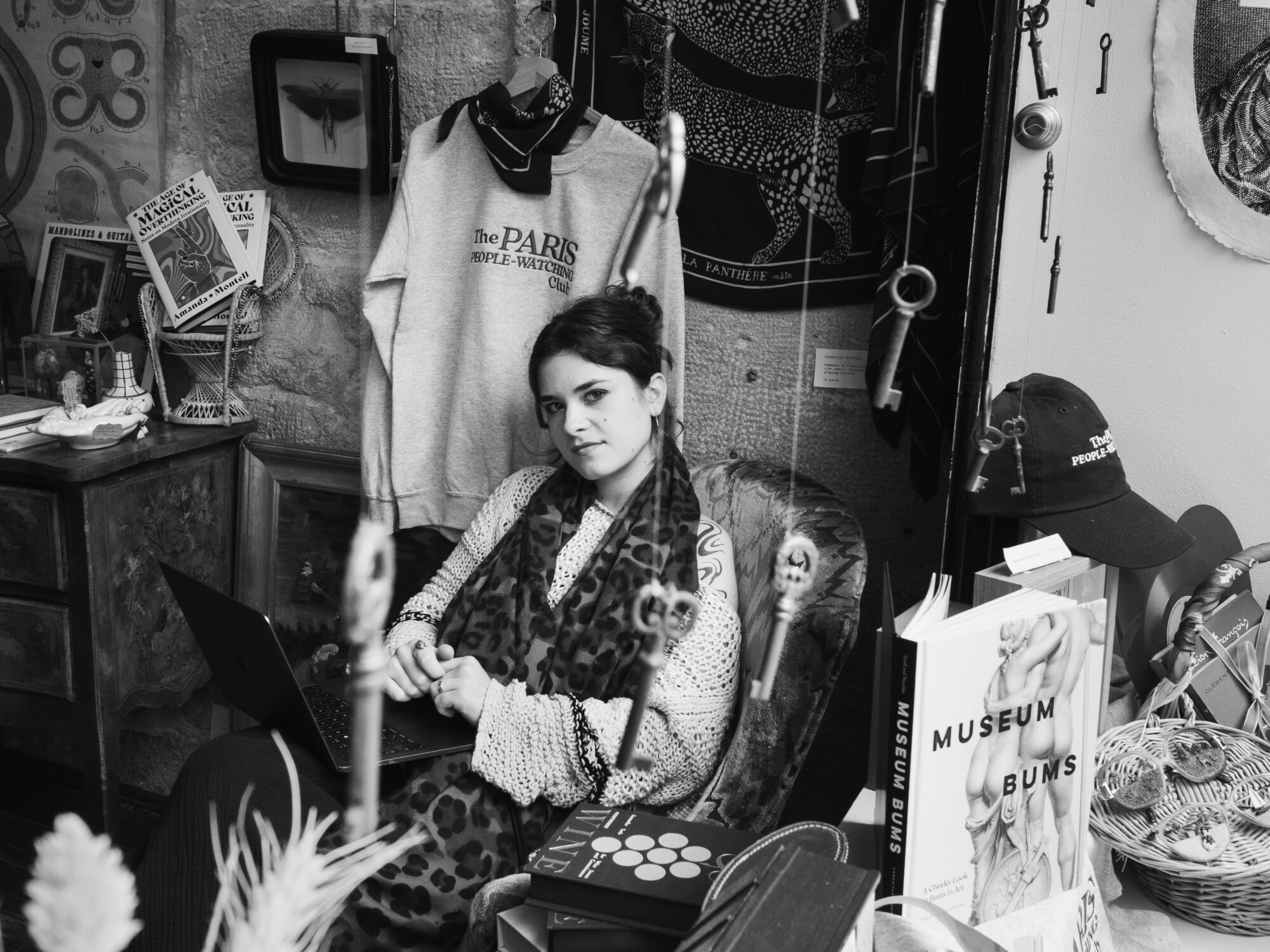 Looking in through a shop window at a seated woman who is looking at the camera