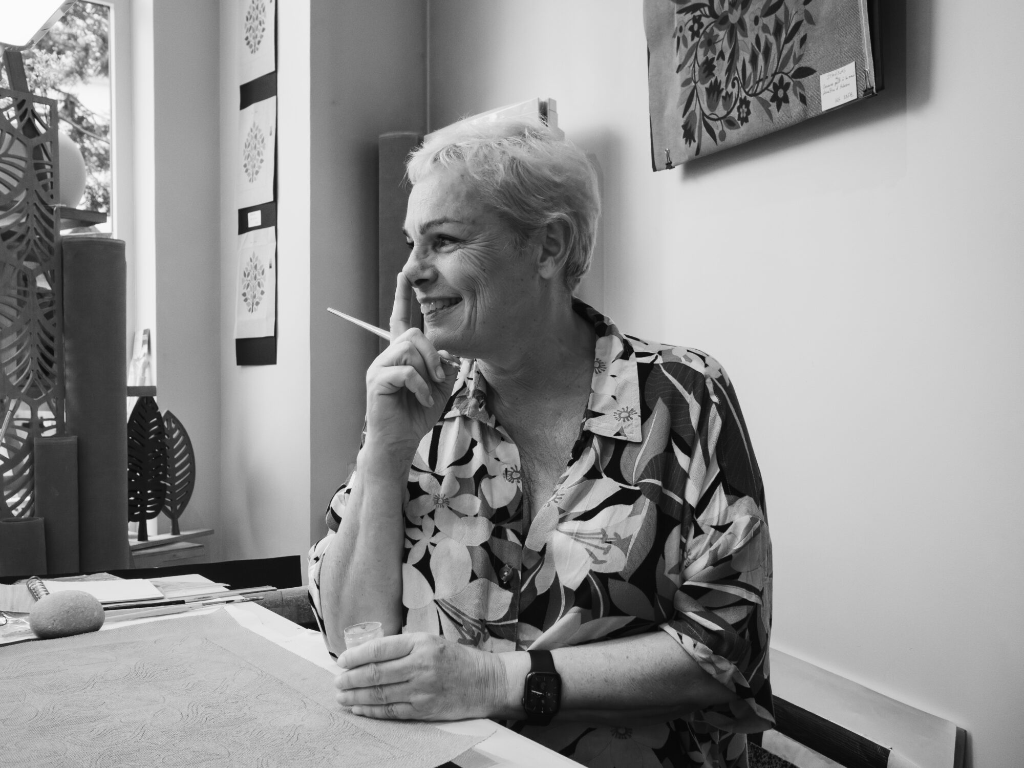 Elegant woman with a paint brush in hand smiling and touching her nose