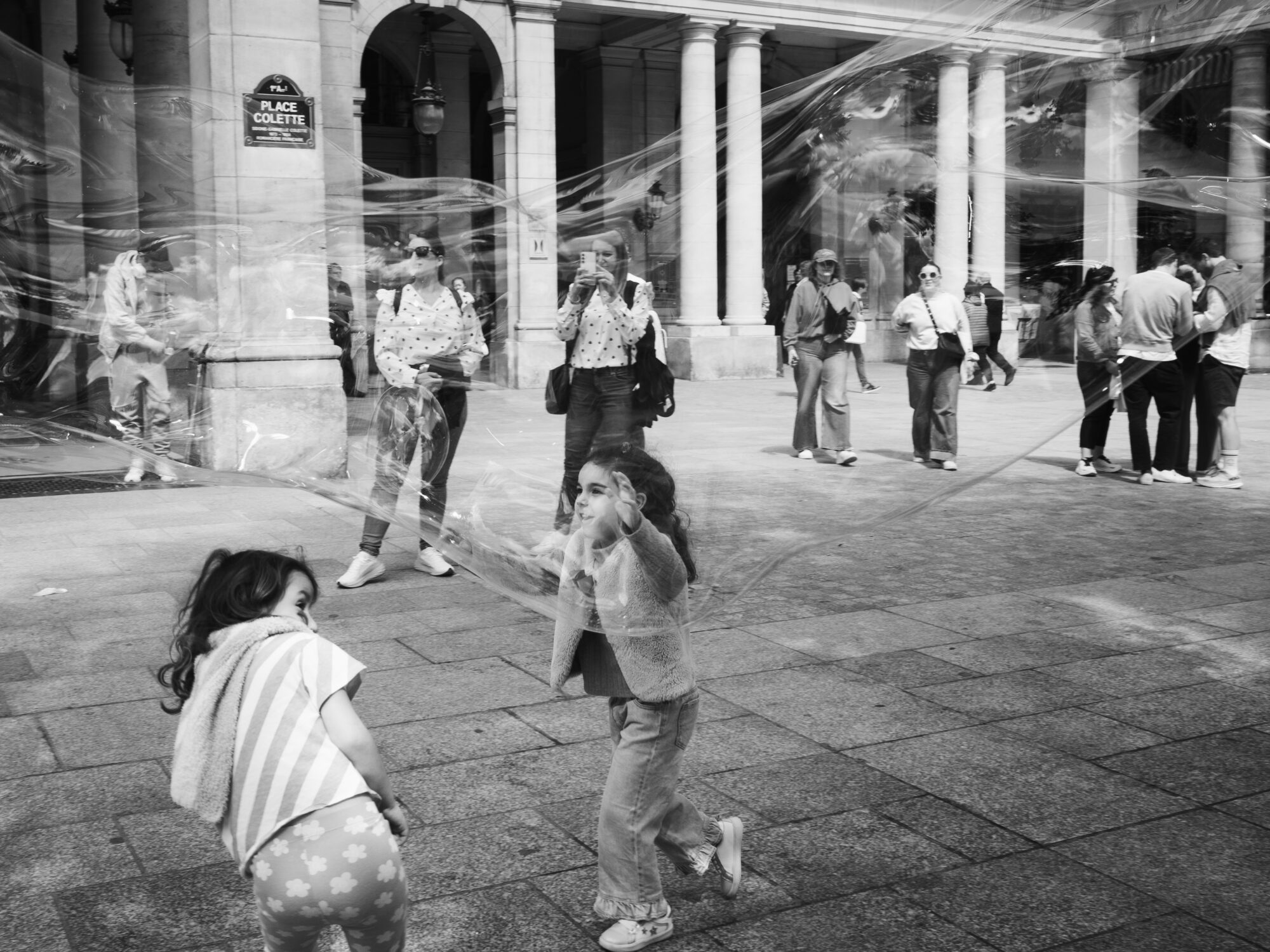 Children playing with a giant bubble that is stretched out between them